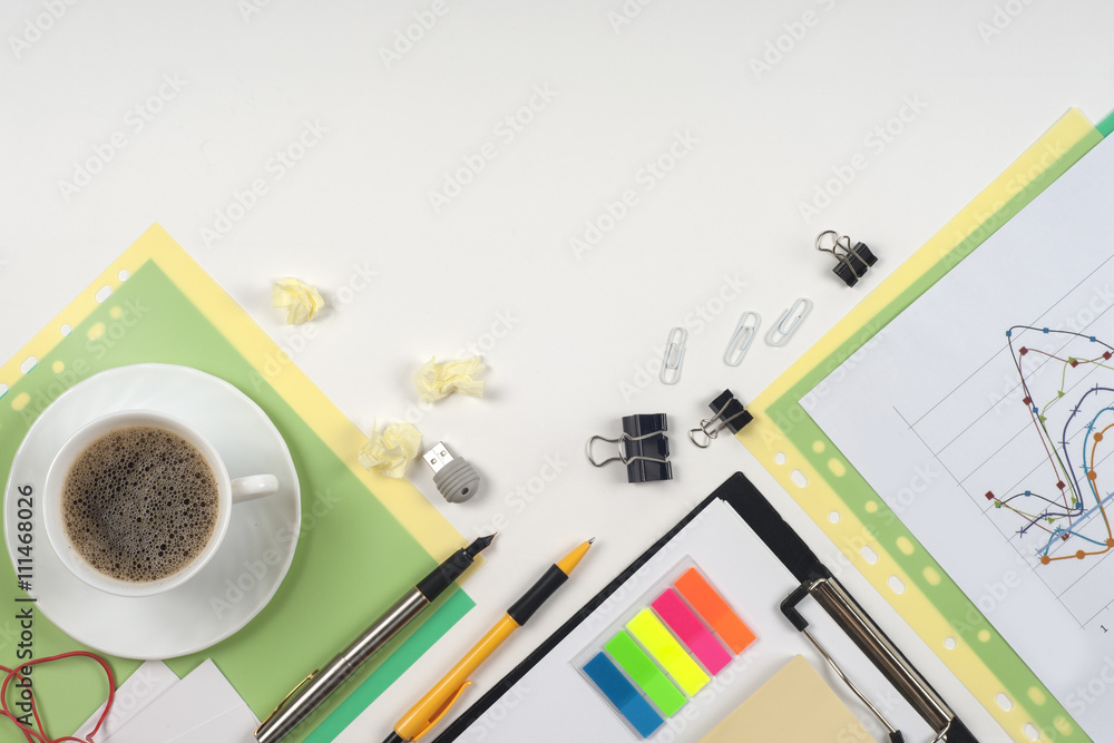 Office table desk with set of colorful supplies, white blank note pad, cup, pen, crumpled paper, flower on white background. Top view and copy space for text Office table desk with set of colorful supplies, white blank note pad, cup, pen, crumpled paper, flower on white background. Top view and copy space for text