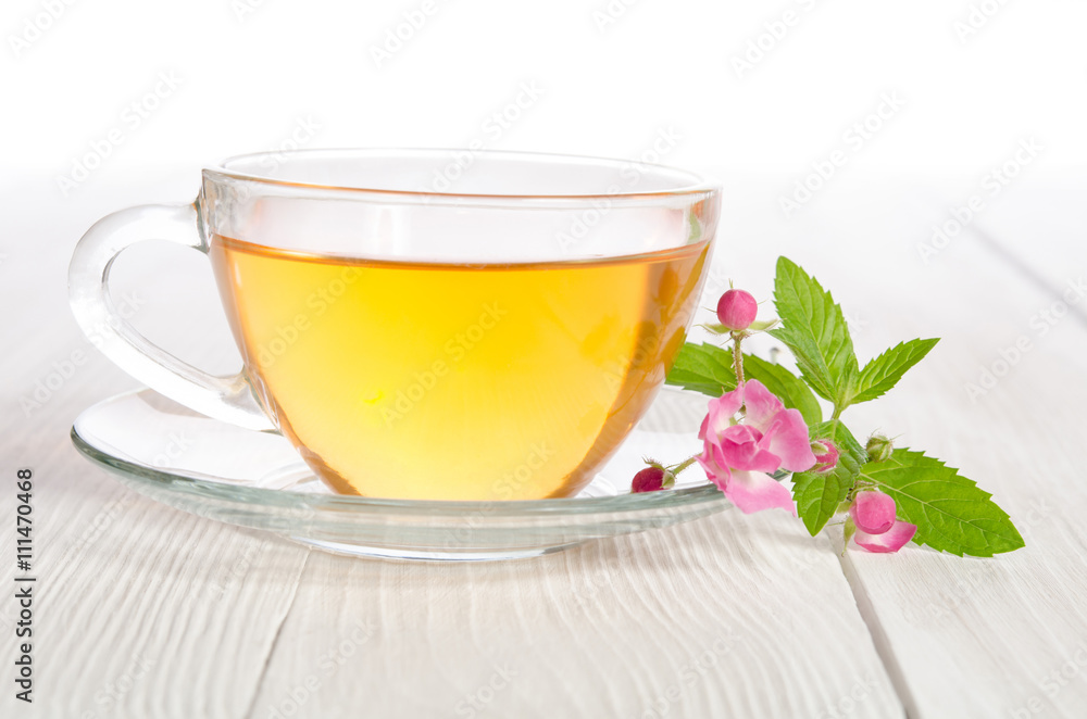 Glass cup of tea with mint and  rose on white wooden table