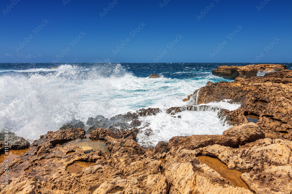 Surging waves break on the rocky shore of Dwejra bay in Gozo, Malta.