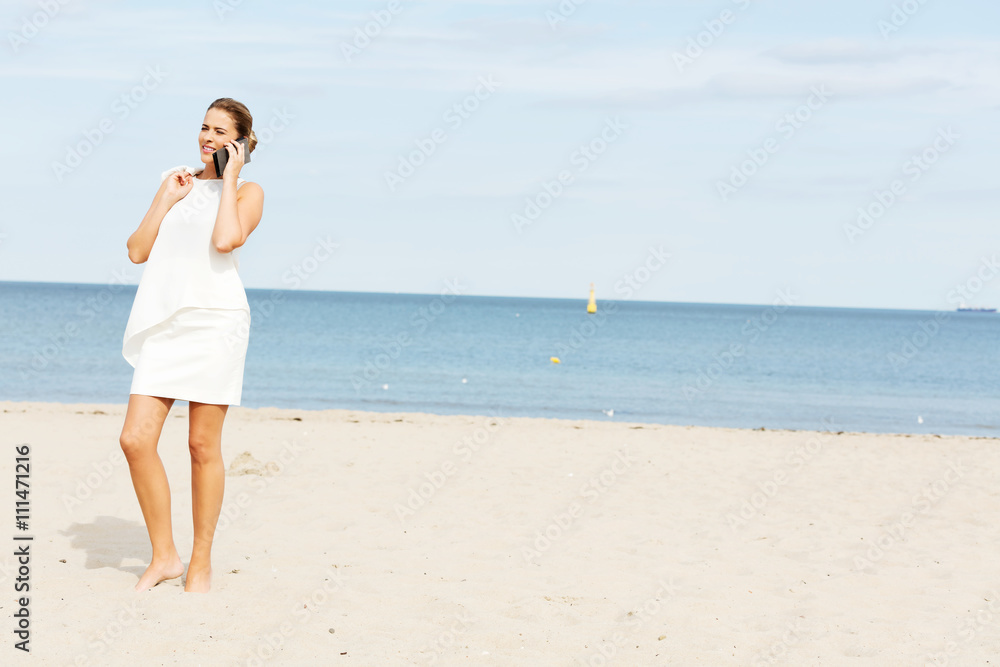 Young elegant beautiful woman talking on the phone on the beach Young elegant beautiful woman talking on the phone on the beach