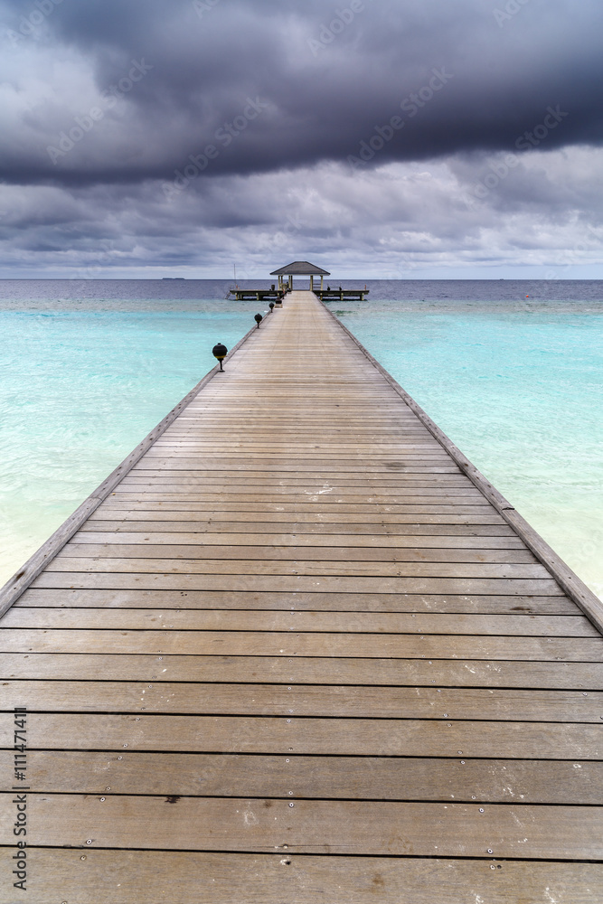 Wooden jetty over the beautiful Maldivian ocean with blue sky Wooden jetty over the beautiful Maldivian ocean with blue sky