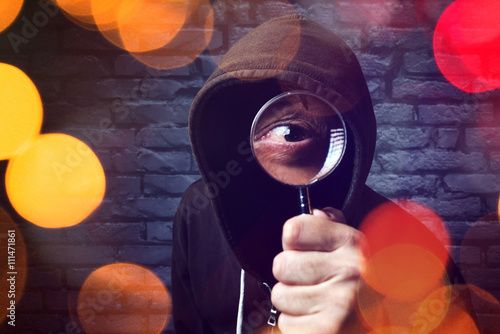 Hooded computer hacker with magnifying glass photo