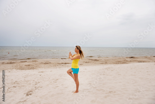 Young woman making yoga exercises on the beach