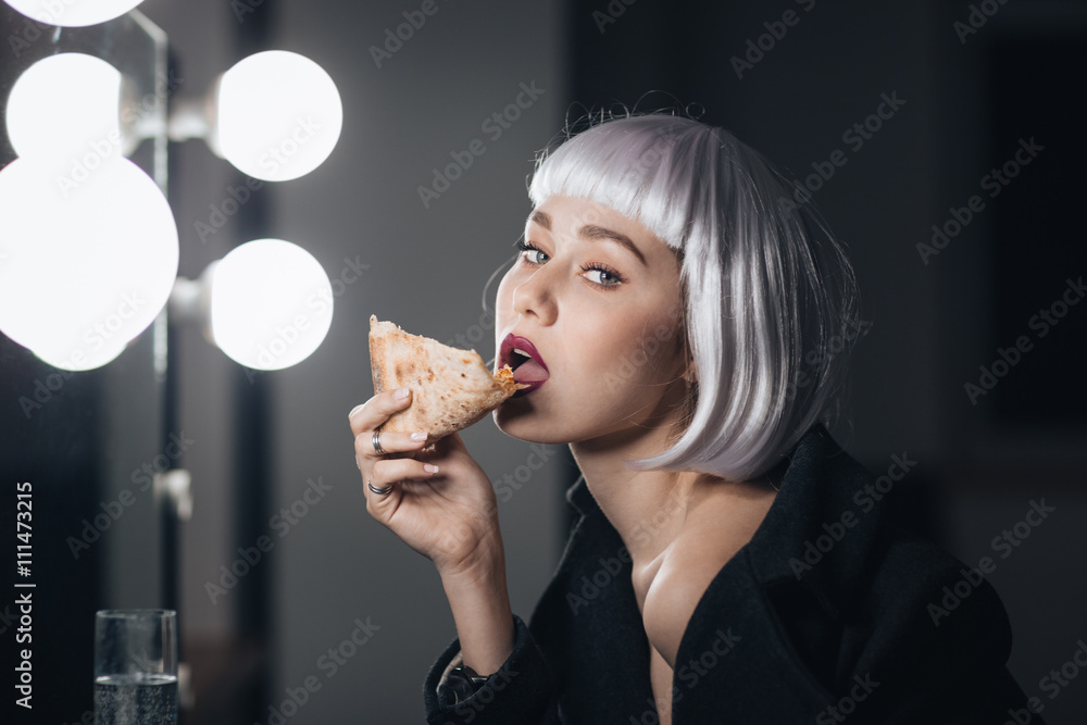 Tempting woman in blonde wig eating pizza and drinking champagne Tempting woman in blonde wig eating pizza and drinking champagne