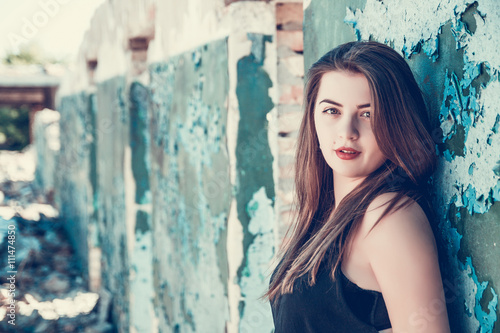 Portrait of Beautiful, long haired, dark-haired girl in a black T-shirt on an abandoned house. Attractive womanposing in old ruined factory house. Copy space. Tone photo