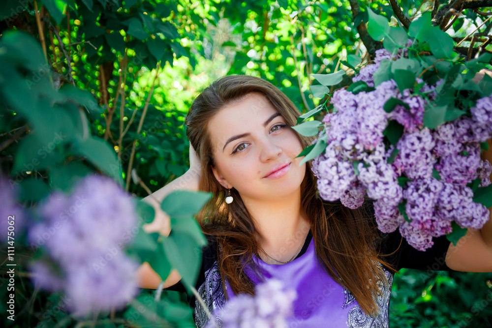 Portrait of Beautiful, long haired, dark-haired girl in purple dress in blooming trees. Attractive romantic woman in flowers of lilac. Warm photo. Portrait of Beautiful, long haired, dark-haired girl in purple dress in blooming trees. Attractive romantic woman in flowers of lilac. Warm photo.