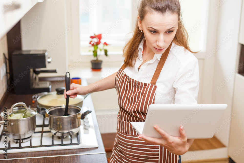 Young woman trying cooking with recipe from laptop Young woman trying cooking with recipe from laptop
