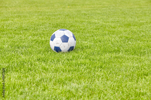Used leather soccer ball on grass  space for text  shallow depth of field.