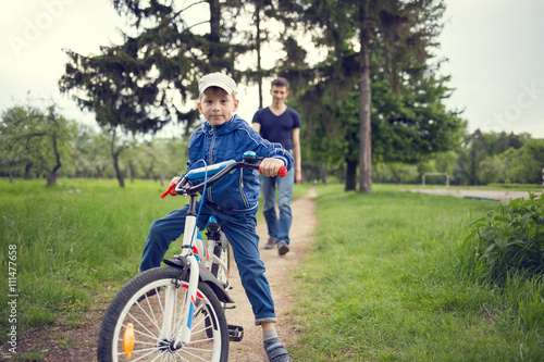 Small boy riding a bike together with his father