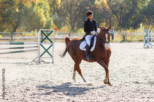 Young girl riding horse in equestrian competition