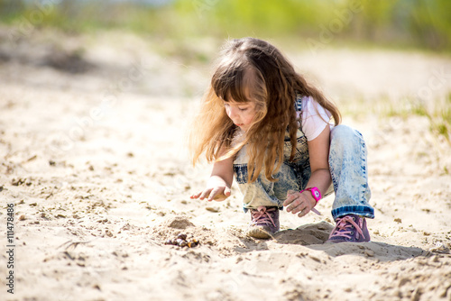 Little girl in denim suit on the sand played © sushytska
