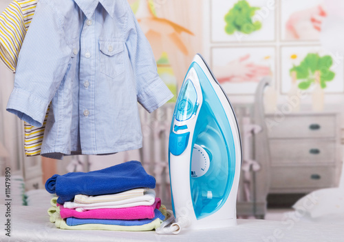 Steam iron and clothes on  background of  child's room.