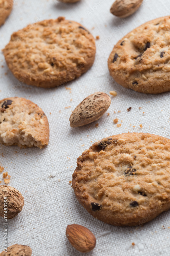 Cookies pile with chocolate chip and almond on light textile background. Delicious morning snacks for breakfast, brunch and lunch. Appetizing, healthy and fast food Cookies pile with chocolate chip and almond on light textile background. Delicious morning snacks for breakfast, brunch and lunch. Appetizing, healthy and fast food