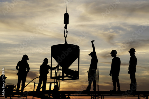 silhouette of construction worker team casting a concrete column by crane up lift bucket on scaffolding  photo