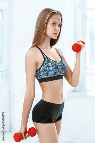 Sporty woman doing aerobic exercise with red dumbbells