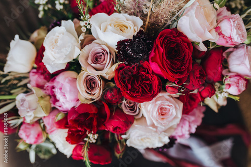 Wedding. Boutonniere. Grain. Artwork. A bouquet of red flowers  pink flowers and greenery with silk ribbons is in the black chair