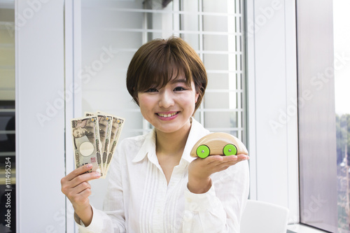 お金とおもちゃの車を持った若い女性