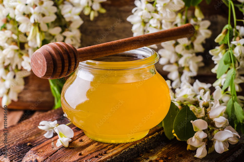 Acacia honey in gar on wooden background. Spring mood. Selective focus. Toned image Acacia honey in gar on wooden background. Spring mood. Selective focus. Toned image