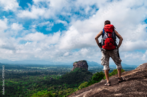 Hiker with backpack enjoying views from top of a mountain. Sigiriya Rock, Pidurangala Rock, Sri Lanka.