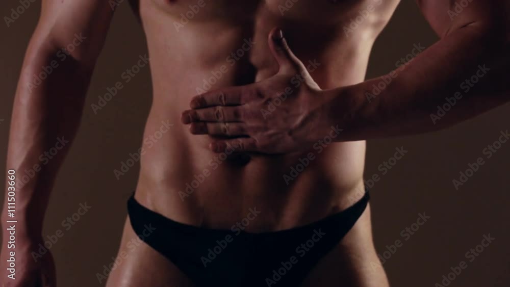 Brutal guy showing his muscles. Touching abs. Graded Brutal guy showing his muscles. Touching abs. Graded