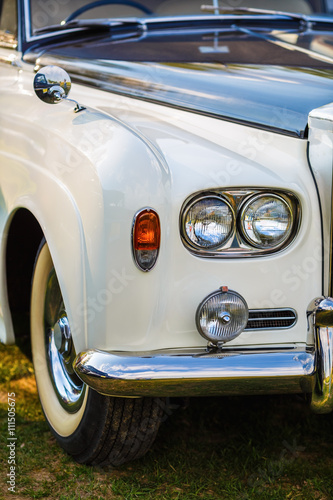 Close-up of the front part of the luxury retro car. Old vintage car. Selective focus on the car's headlight.