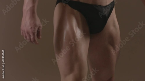 Brutal guy showing his muscles. Quadriceps (leg muscles). Ungraded