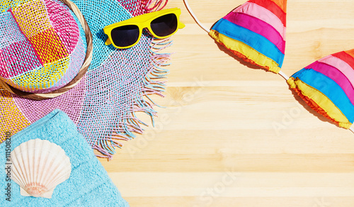 Summer beach vacation set. Colorful straw hat,bikini,sunglasses and towel with shell on the wooden table. 