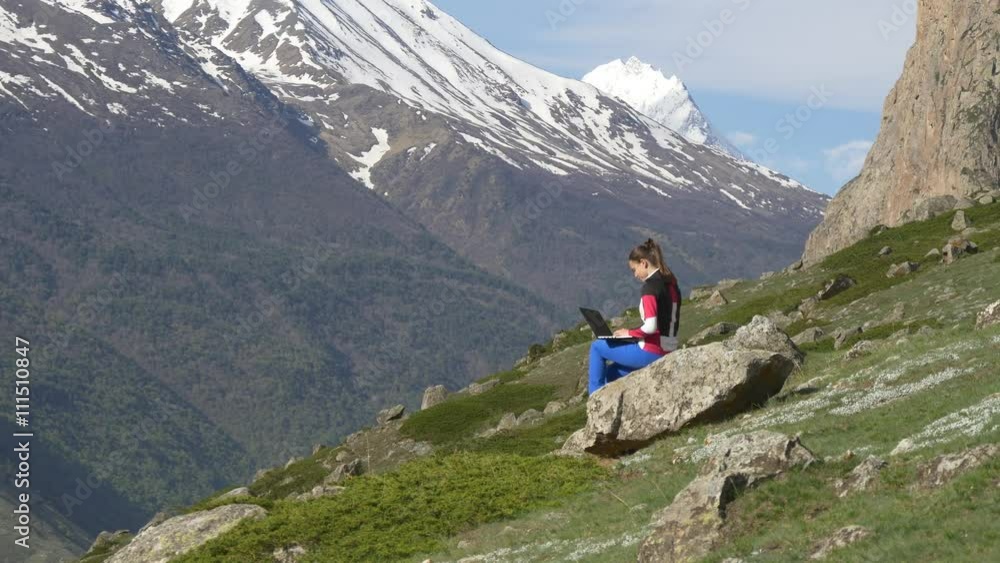 Woman with laptop on the background of snowy peak Woman with laptop on the background of snowy peak
