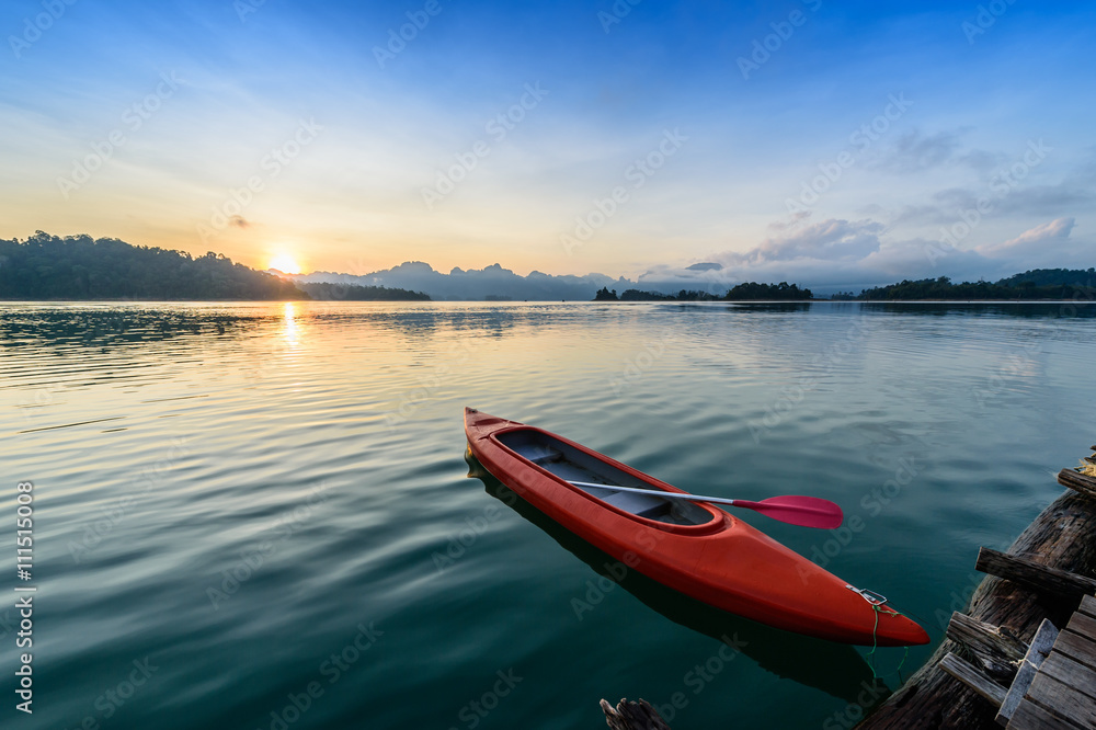 Canoe floating on the calm water under amazing sunrise Canoe floating on the calm water under amazing sunrise
