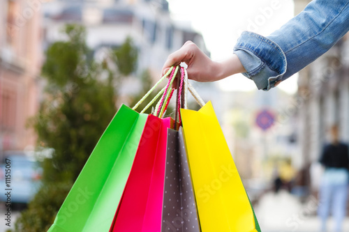 closeup picture of multi colored shopping bags with a hand