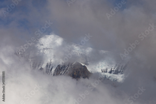 Alpine Mountain landscape covered by snow and clouds.
