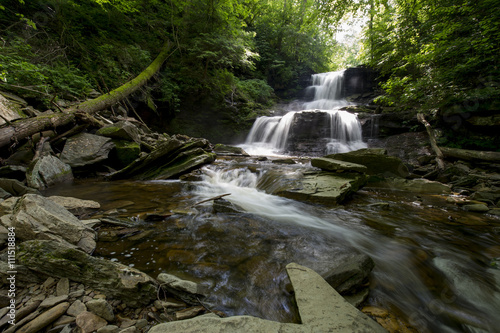 A long exposure of a waterfall scene in a forest of green trees.