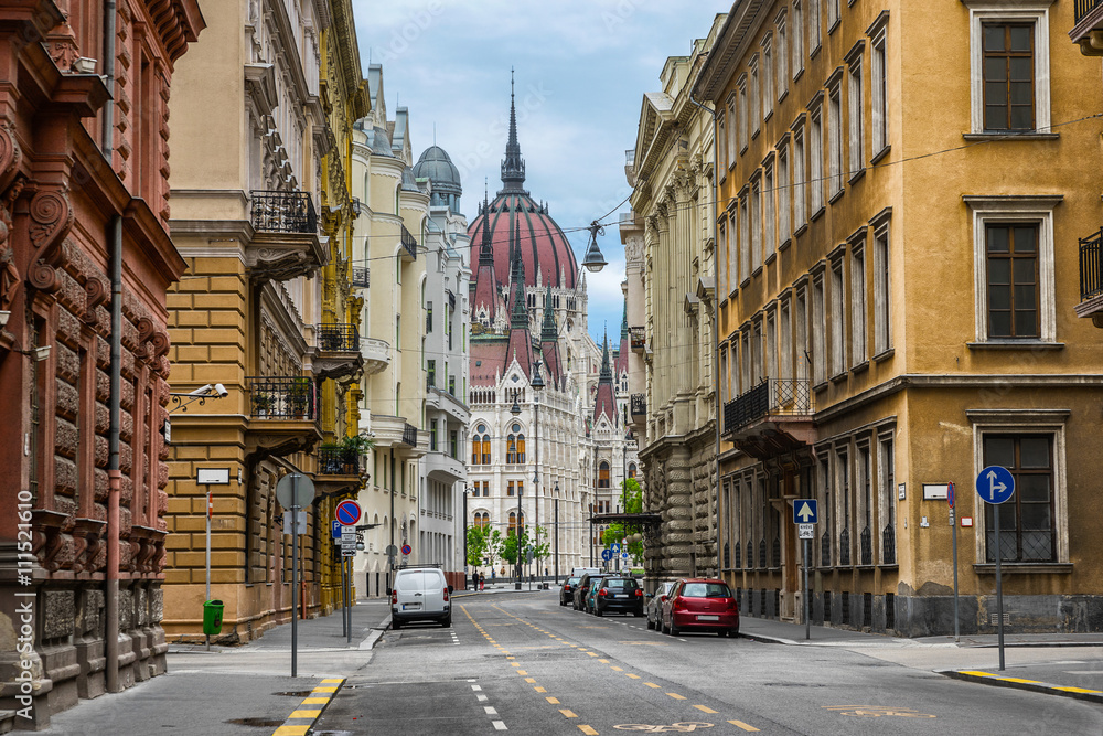 Obraz premium The Hungarian Parliament from one of the colourful streets in Budapest