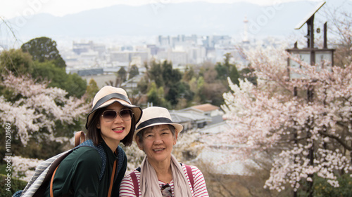 Asian women portrait - Senior mother and adult daughter looking and smiling to the camera. Background is Landscape Kyoto shooting from Kiyomizu-dera Temple, Kyoto, Japan