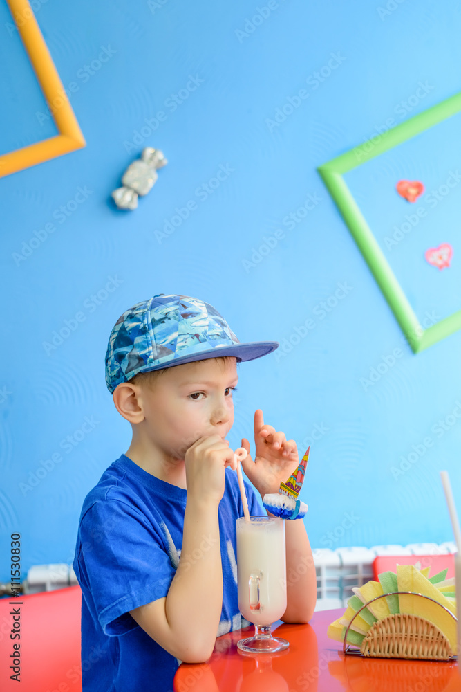 Trendy excited little boy enjoying a milkshake