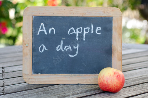 Fototapeta Naklejka Na Ścianę i Meble -  An apple a day written on chalk board with apple in front