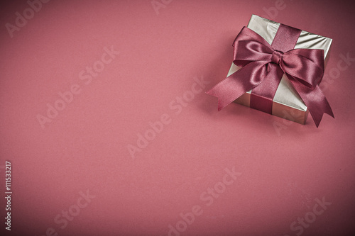 Gift container with tied bow on red background holidays concept