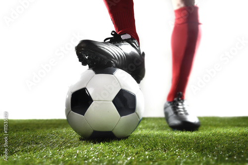 legs feet of football player in red socks and black shoes posing with the ball playing on green grass pitch © Wordley Calvo Stock