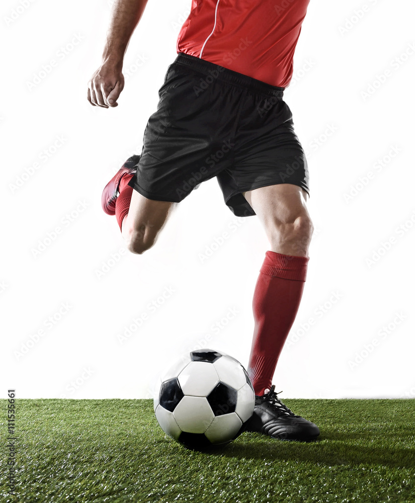 close up legs of football player in red socks and black shoes running and kicking the ball