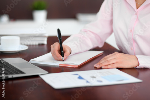 Closeup of a business woman writing in a notebook