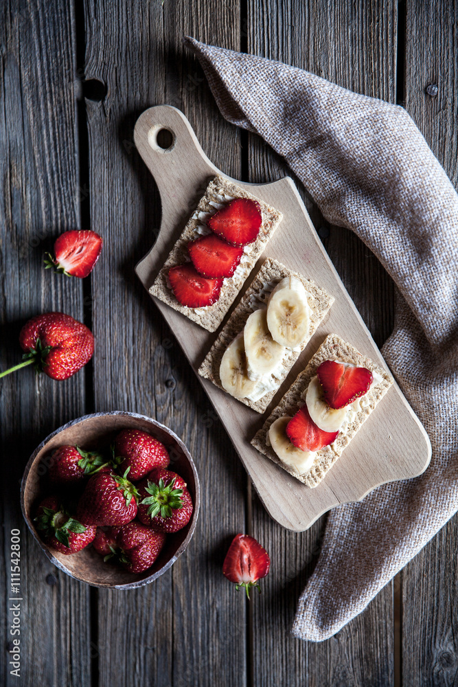 Fruity toast on wooden background. Strawberries, bread, butter and cheese.Vintage style