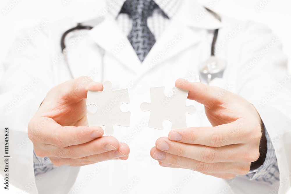 Male doctor trying to connect puzzle parts - close up studio shot