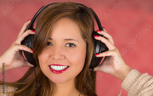 Happy face woman with hands on headphones, pink background