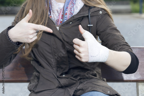Blonde woman with a injured wrist wrapped in an bandage  feeling good  getting better  outdoors.