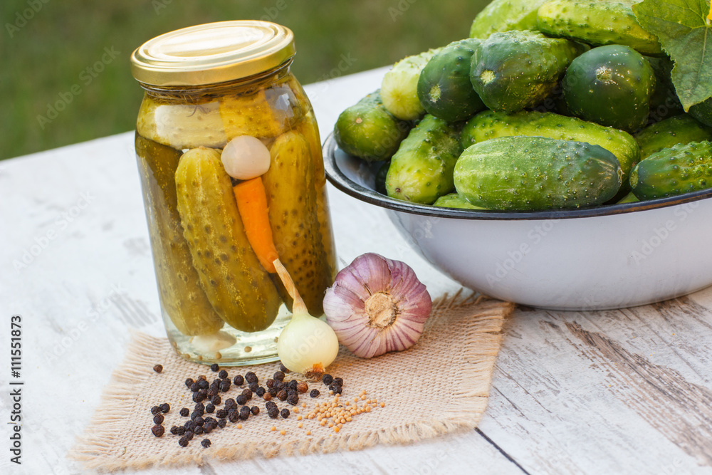 Cucumbers in metal bowl, spices for pickling and jar pickled cucumbers on table Cucumbers in metal bowl, spices for pickling and jar pickled cucumbers on table
