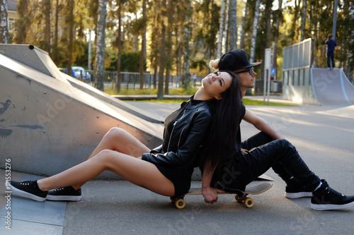 Modern casual couple posing with skateboard.