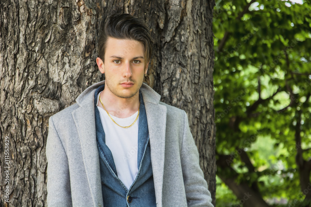 Handsome young man leaning against tree Handsome young man leaning against tree