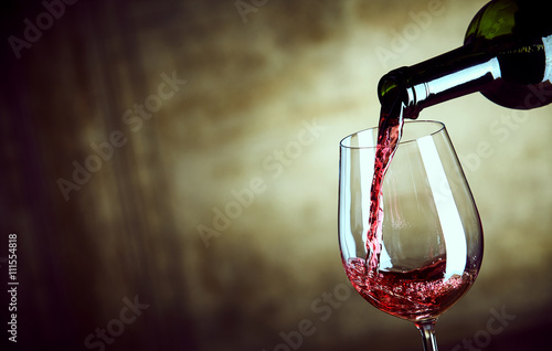 Serving a single glass of red wine from a bottle photo
