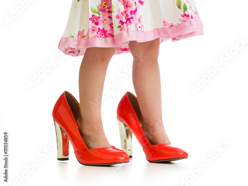 kid girl trying mother's shoes on her legs