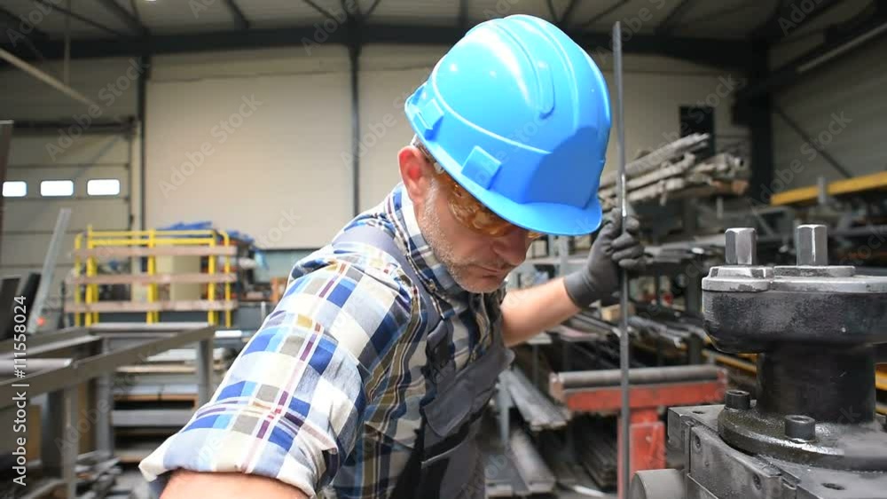 Metalworker with hardhat working on machine Metalworker with hardhat working on machine